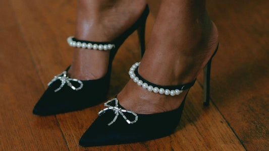 Close up of model wearing black pointed heels with sparkly bows